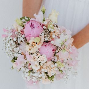 eine Frau hält einen Blumenstrauß aus rosa und weißen Blumen