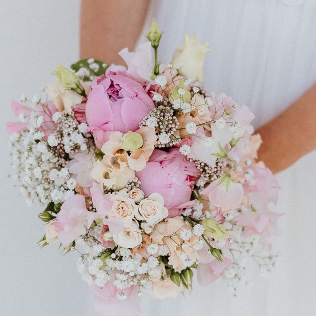 eine Frau hält einen Blumenstrauß aus rosa und weißen Blumen in ihren Händen