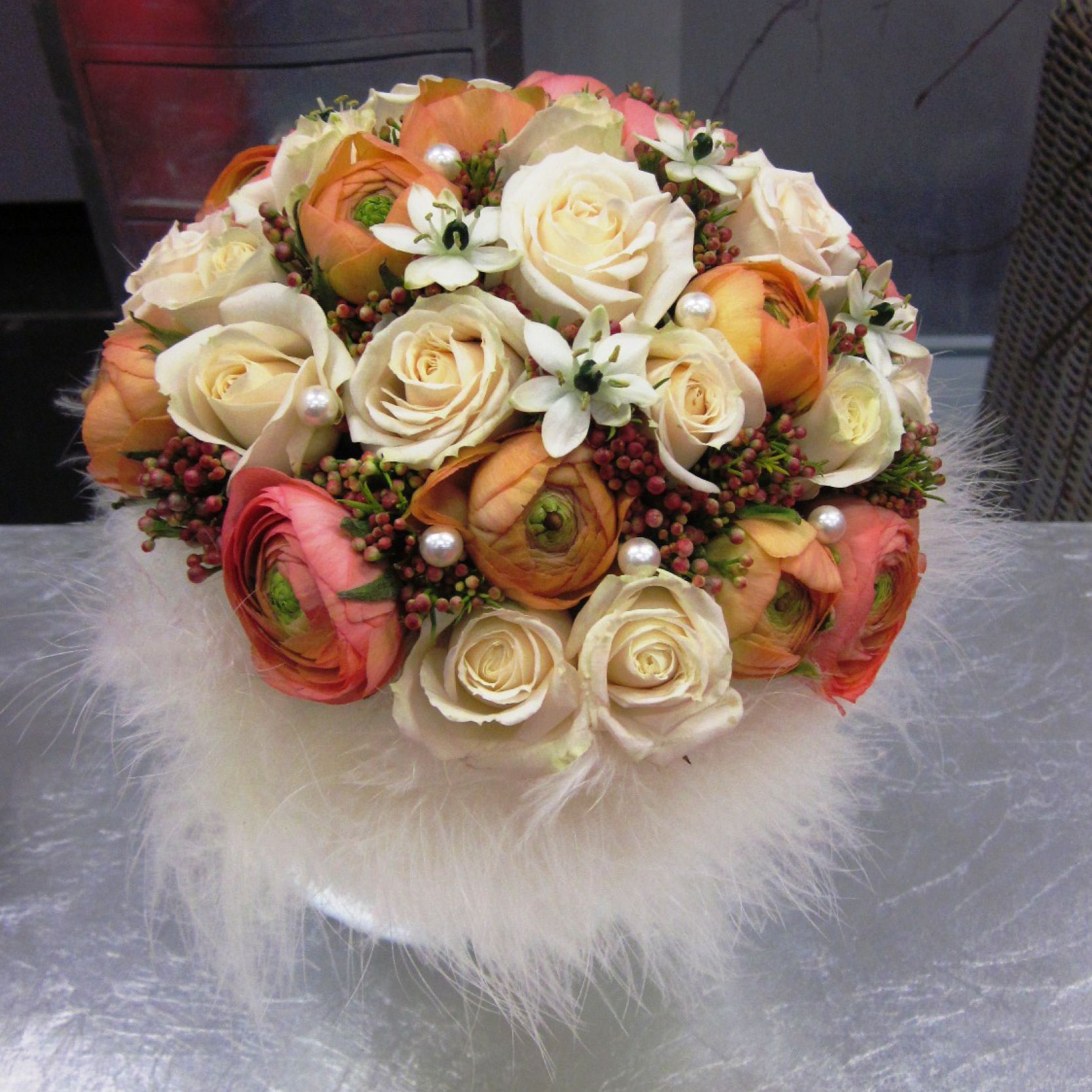 ein Blumenstrauß aus rosa und weißen Rosen sitzt auf einem weißen Pelzkissen