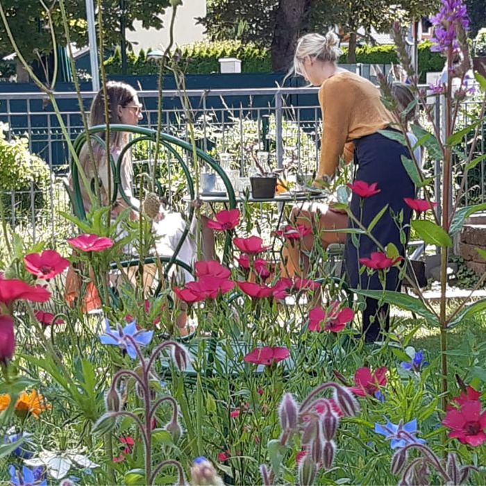 Zwei Frauen sitzen an einem Tisch in einem Blumenbeet .
