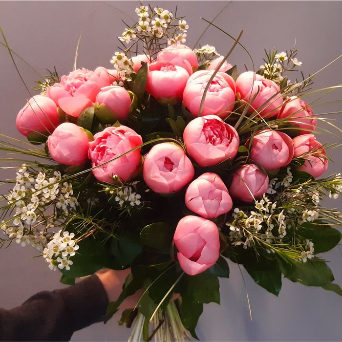 eine Person hält einen Blumenstrauß mit rosa und weißen Blumen