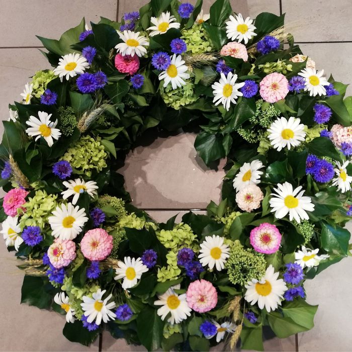 ein Kranz aus rosa und lila Blumen und grünen Blättern