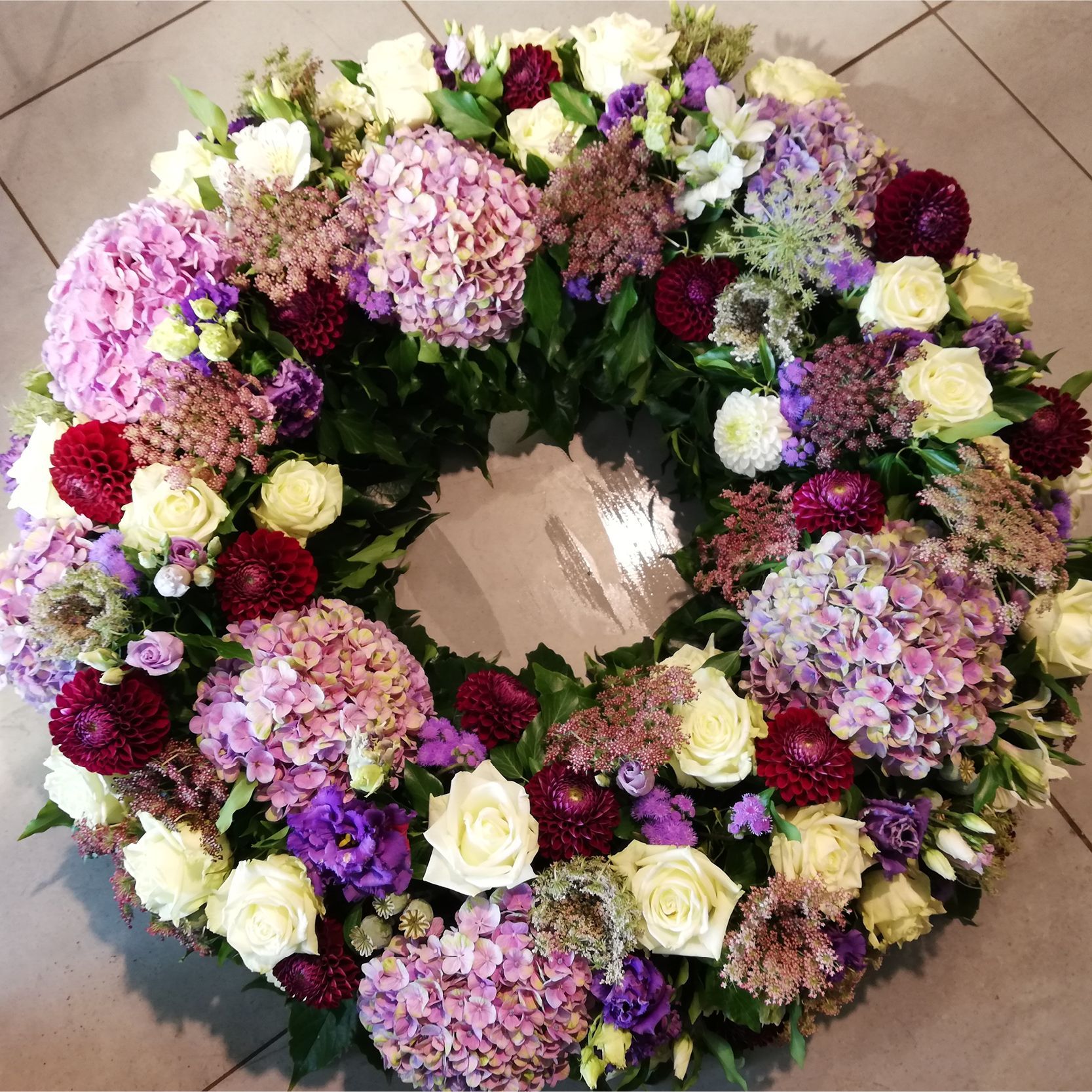 ein Kranz aus lila und weißen Blumen liegt auf dem Boden