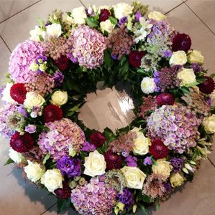 ein Kranz aus lila und weißen Blumen liegt auf dem Boden