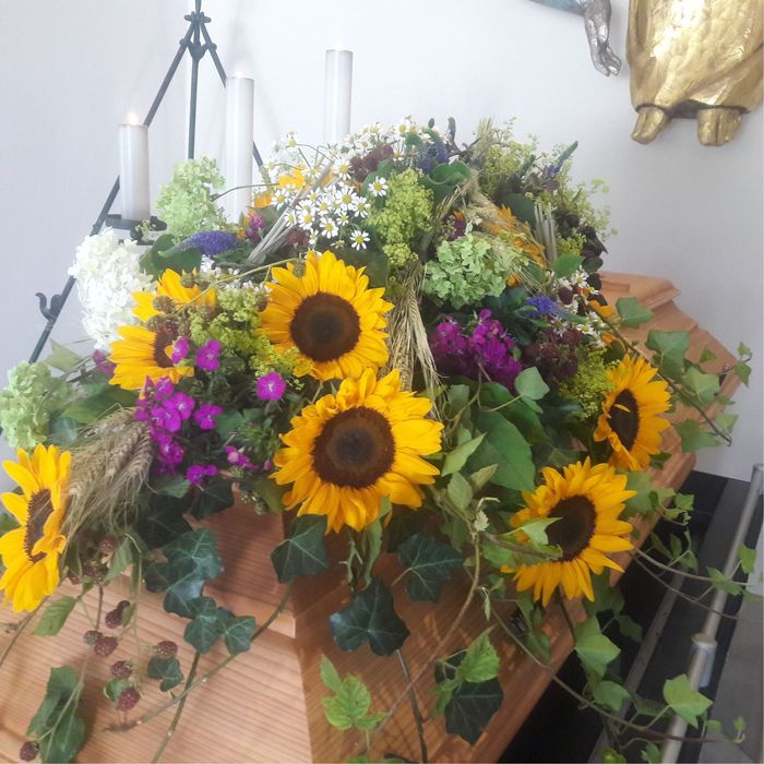ein sarg mit bunten blumen und kerzen darauf .