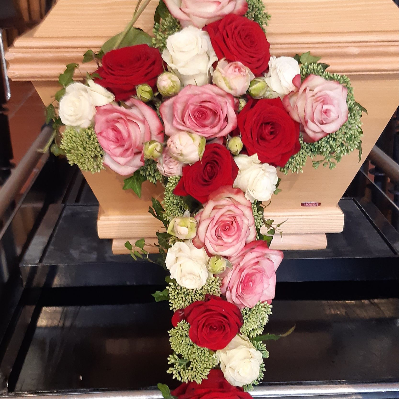 ein sarg mit roten und rosa rosen darauf