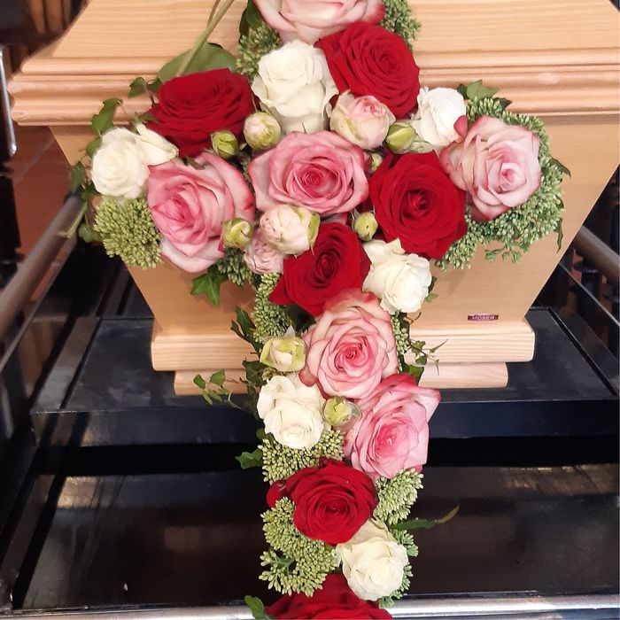ein sarg mit roten und rosa rosen darauf