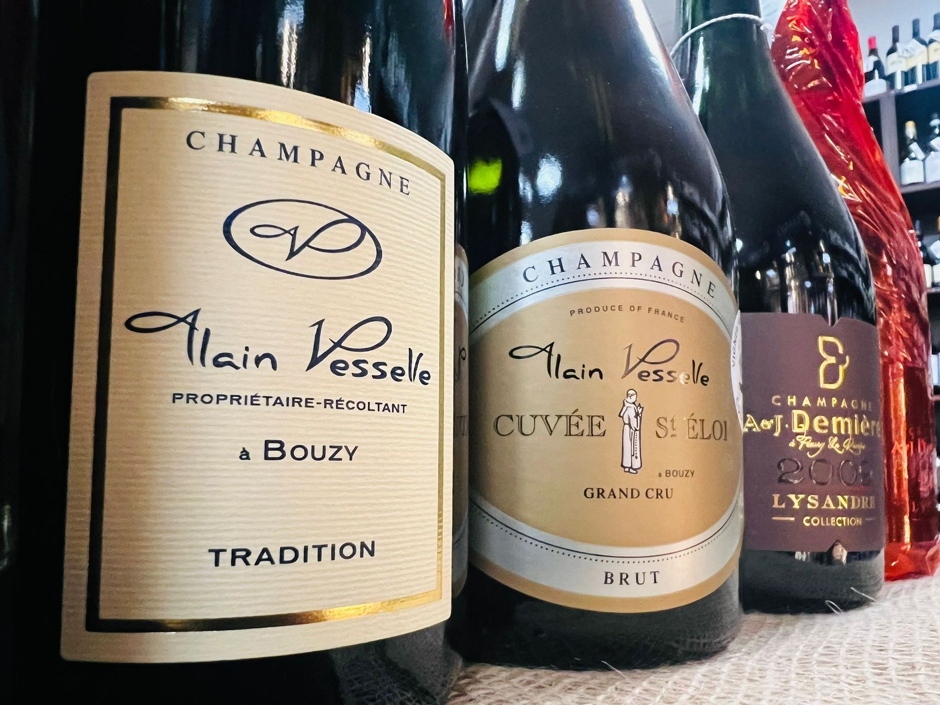 Su un tavolo, tre bottiglie di Champagne di Alain Vesselle: Tradition, Cuvée e un'altra etichetta.