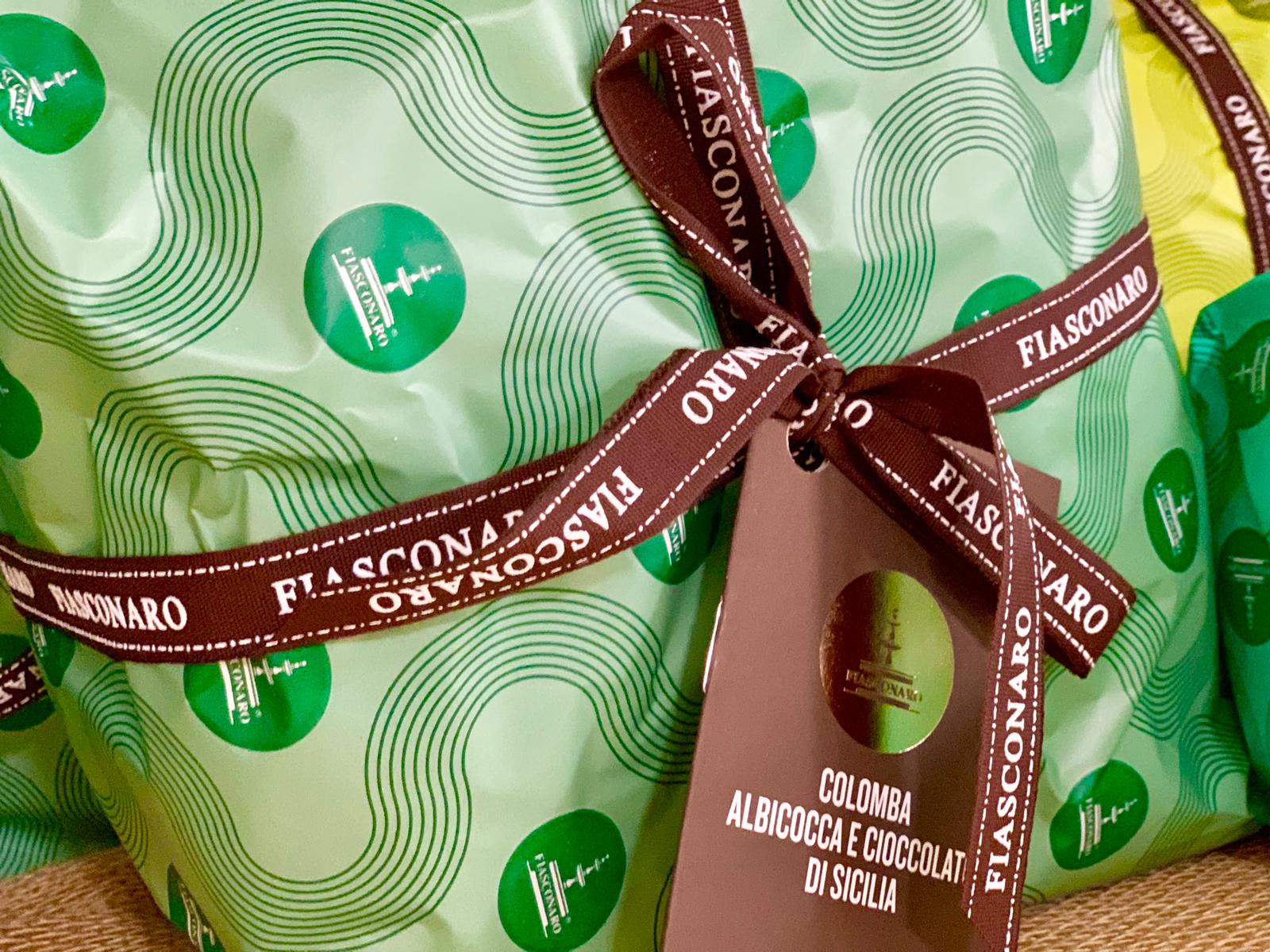 Una confezione regalo Fiasconaro avvolta in carta fantasia verde chiaro con nastro marrone e cartellino del prodotto.