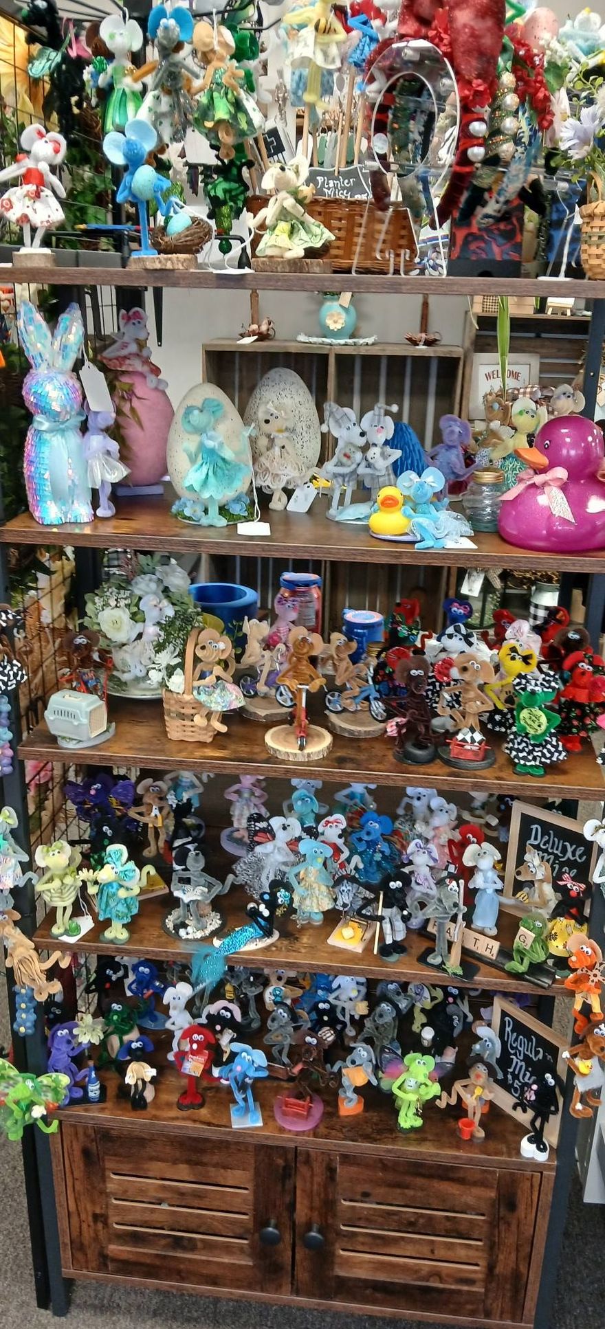 Tiered display of colorful handmade jewelry and accessories on a round white stand in a shop.
