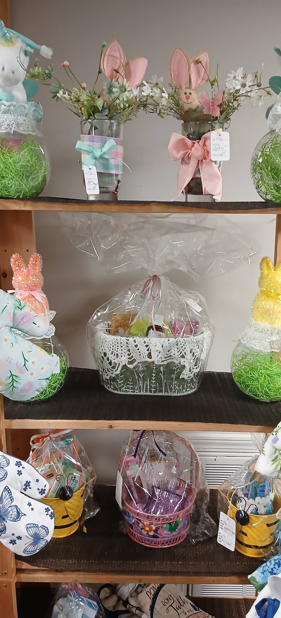 Decorative Easter-themed bunny baskets and floral arrangements displayed on a wooden shelf
