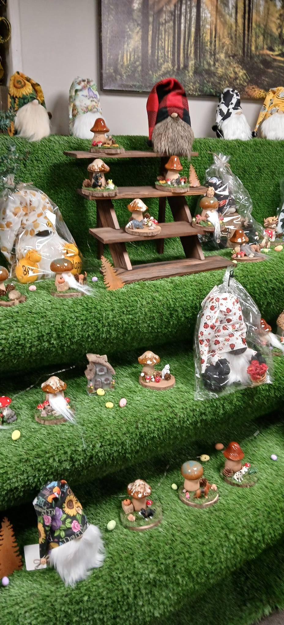 Miniature fairy garden with tiered moss steps, tiny figurines, mushrooms, and a red bird centerpiece