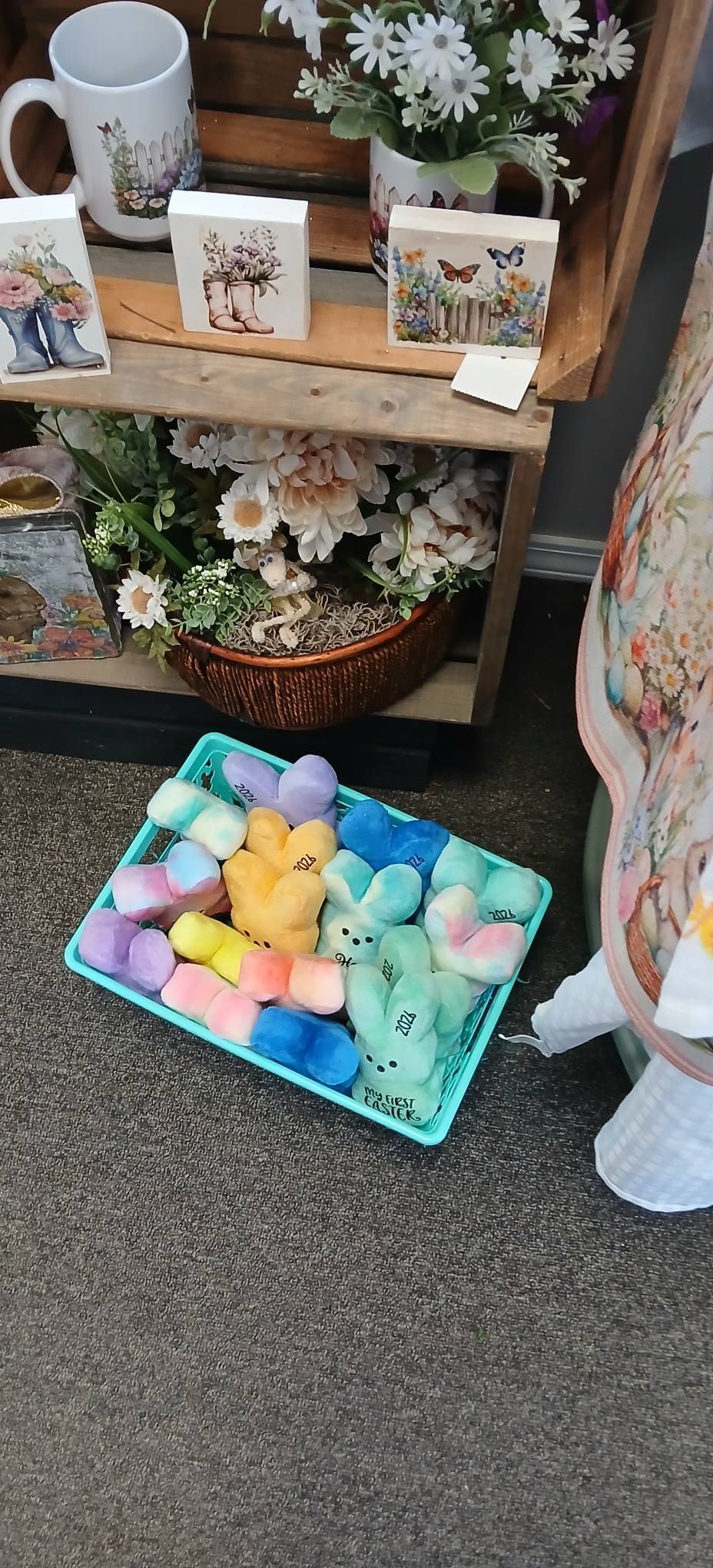 Pastel marshmallow candies in a blue tray on a store shelf beside floral decor