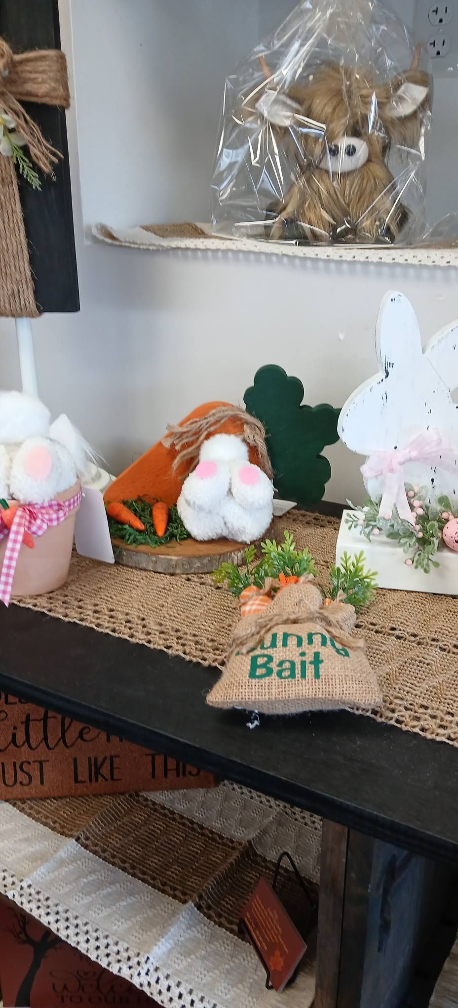 Easter bunny figurines and spring decor on a shelf with a “Bunny Bait” sign