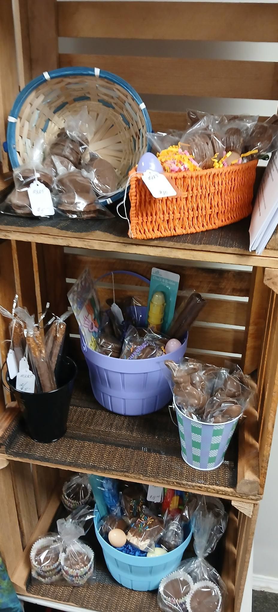 Wooden shelf with assorted baskets of craft and household items in blue, orange, and wicker containers
