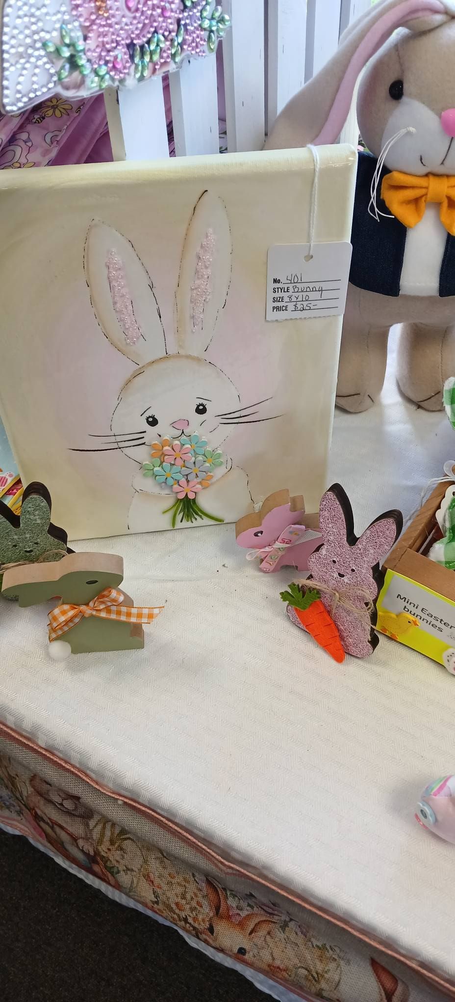 Easter-themed tabletop display with a bunny drawing, pastel eggs, and a small stuffed toy on a table