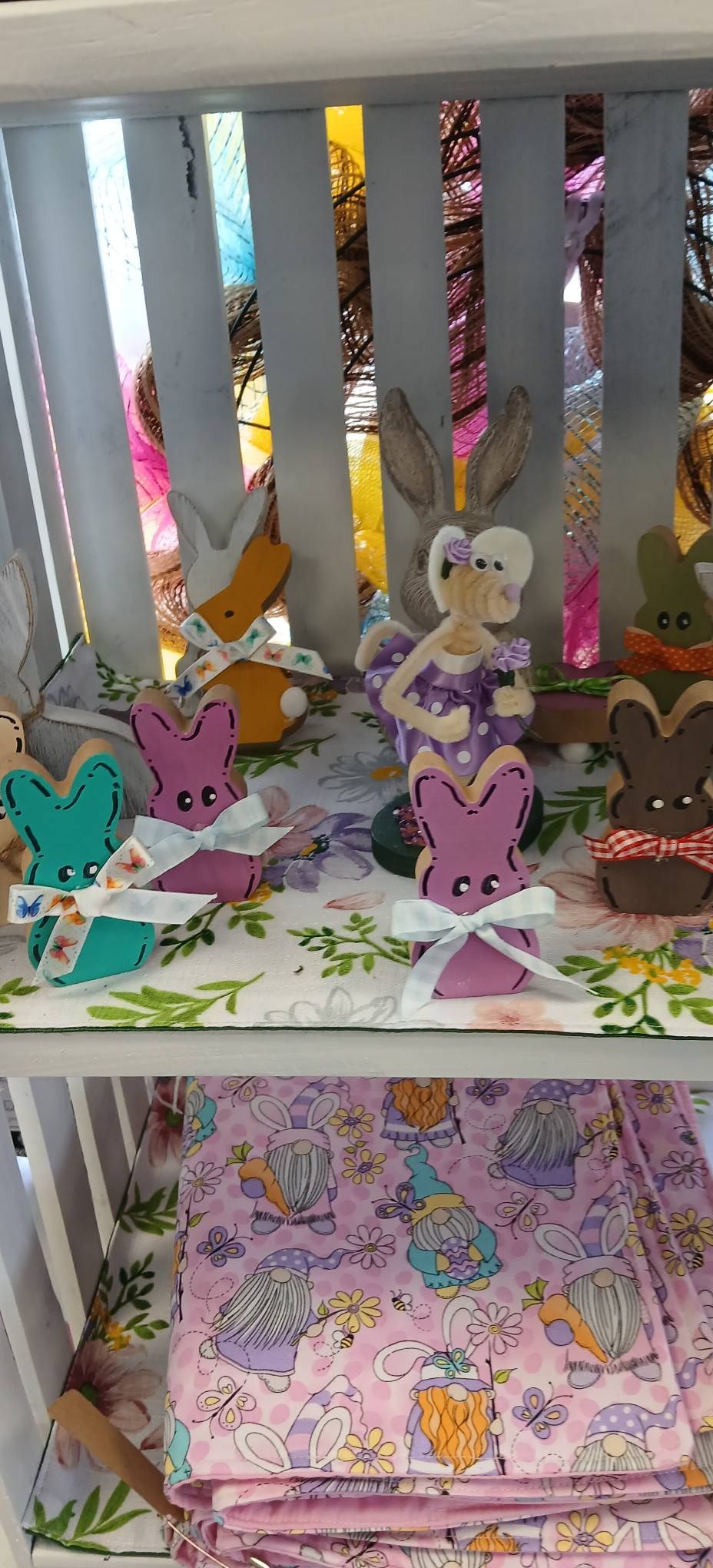 Colorful paper bunny crafts on a shelf with pastel decorations and a pink patterned box below