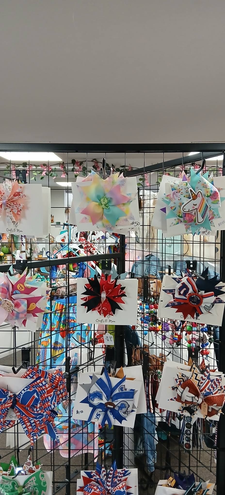 Colorful handmade pinwheel decorations displayed on a metal rack in a market stall