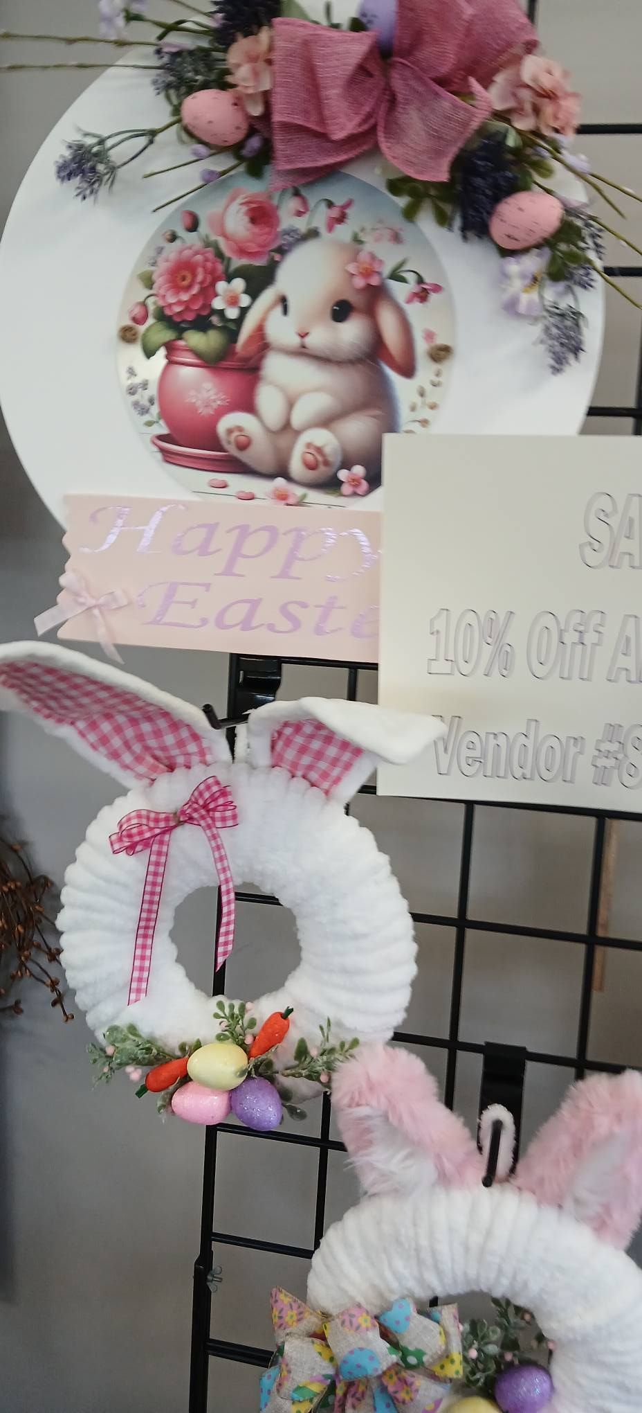 Pastel pink Easter wreath with bunny and flowers hanging on a display wall