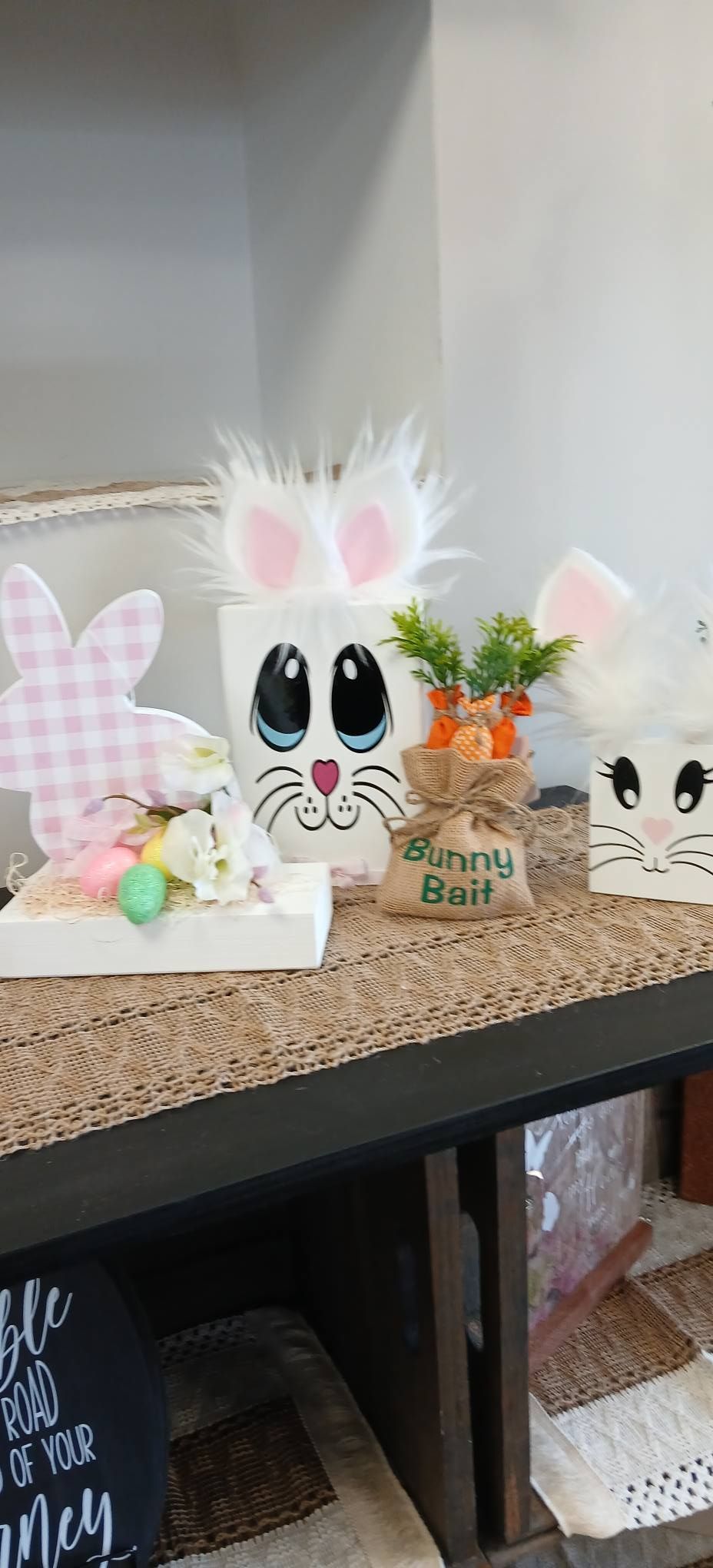 Easter bunny decor with pastel eggs and flowers on a shelf, including a white bunny with big eyes and pink ears