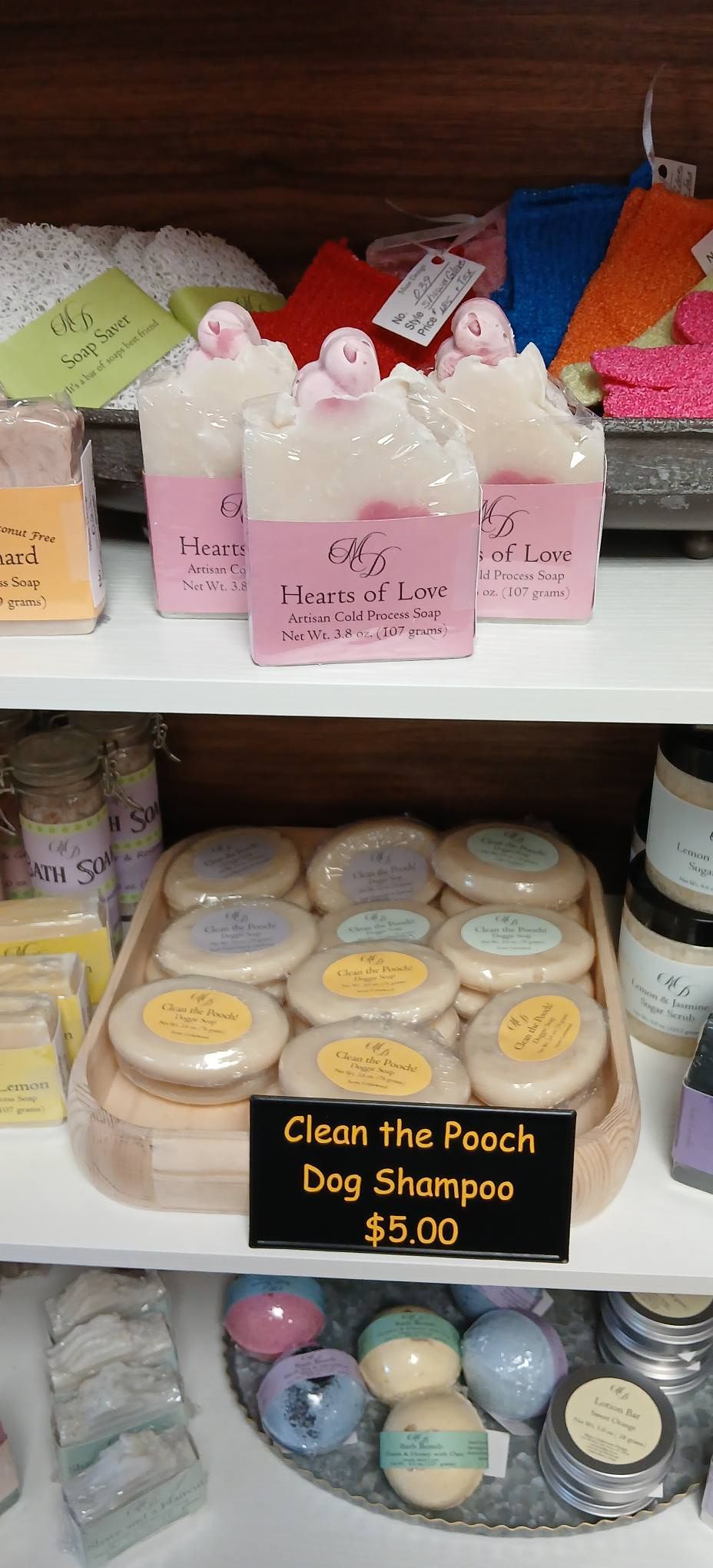 Small pastel decorative soaps on a shelf, with a sign reading “Clean the Pooch Dog Shampoo $5.00.”