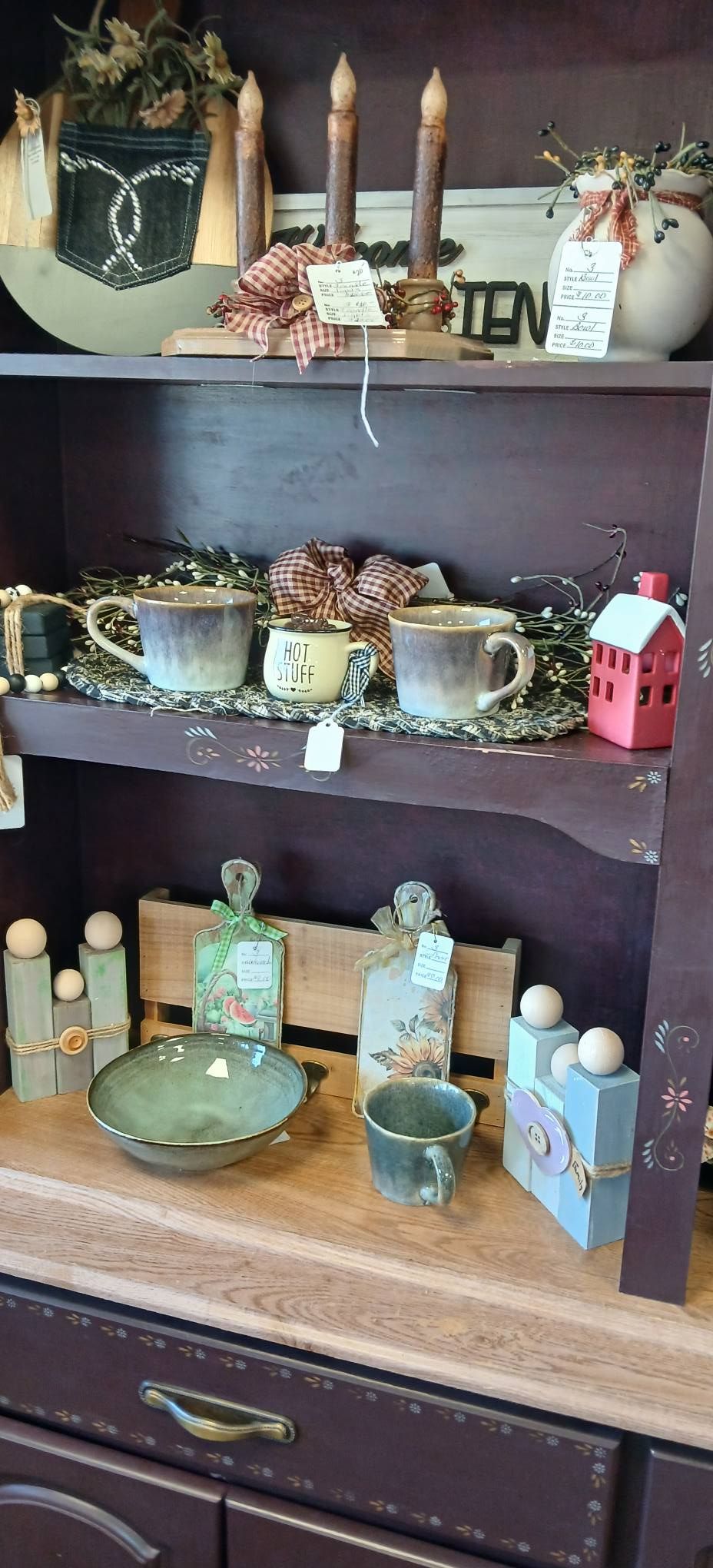 Shelves filled with vintage teapots, mugs, and ceramic dishes on a wooden cabinet