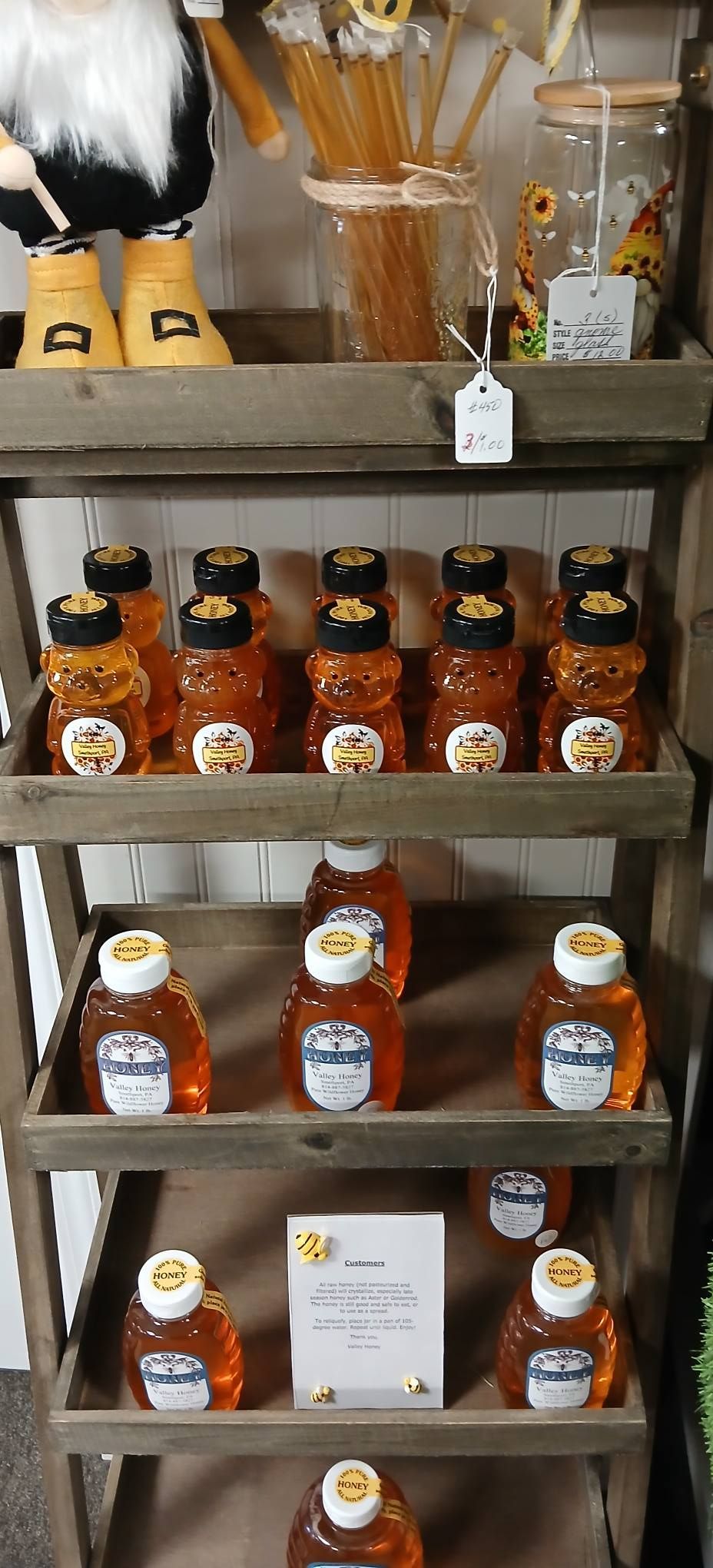 Shelved jars of honey and honey dippers in a market display