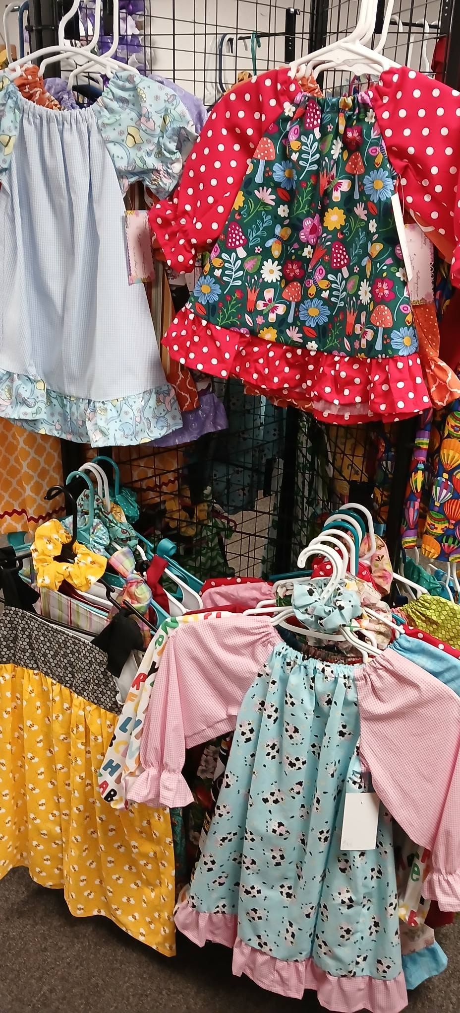 Colorful children’s dresses and outfits hanging on a rack at a market stall
