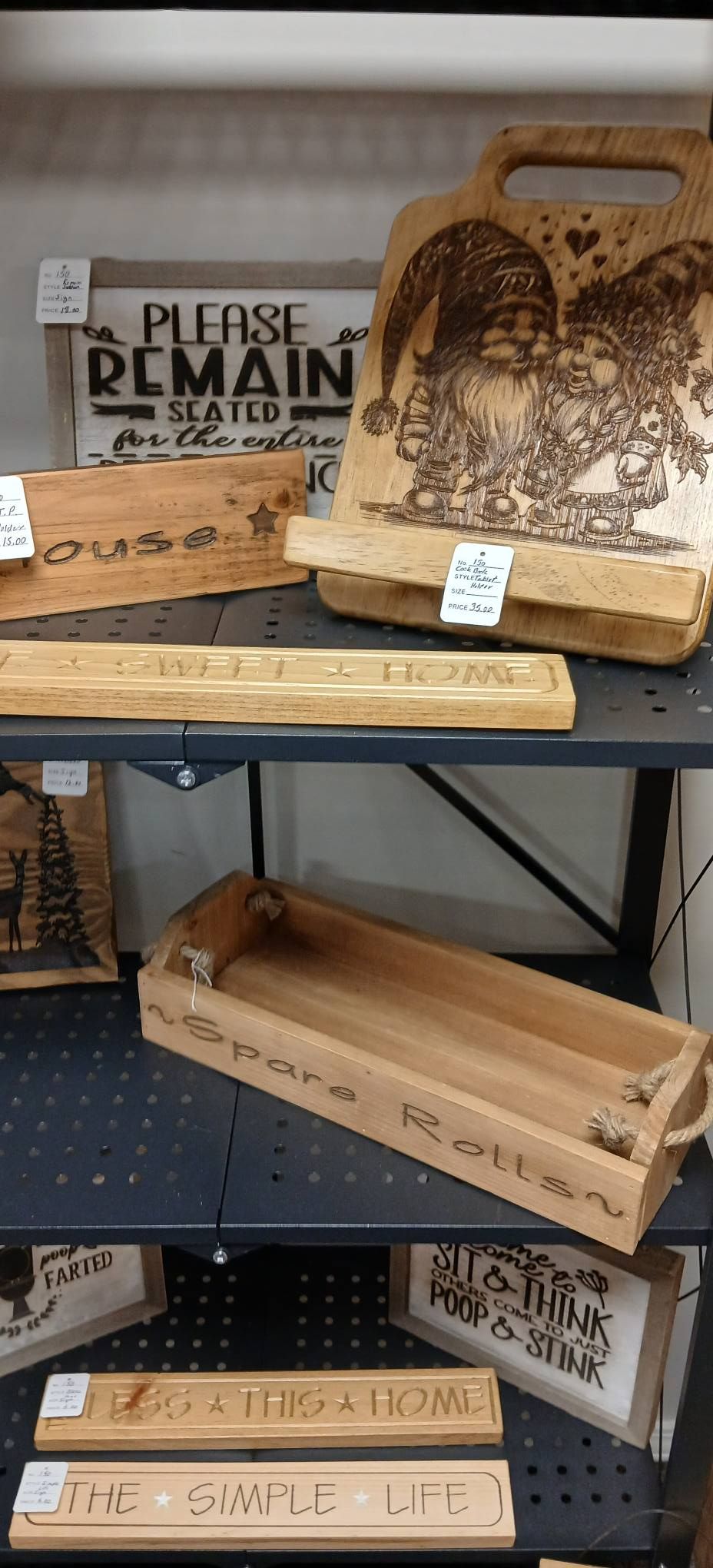 Rustic wooden bakery crates and trays displayed on metal shelving, with printed labels and a carved platter.