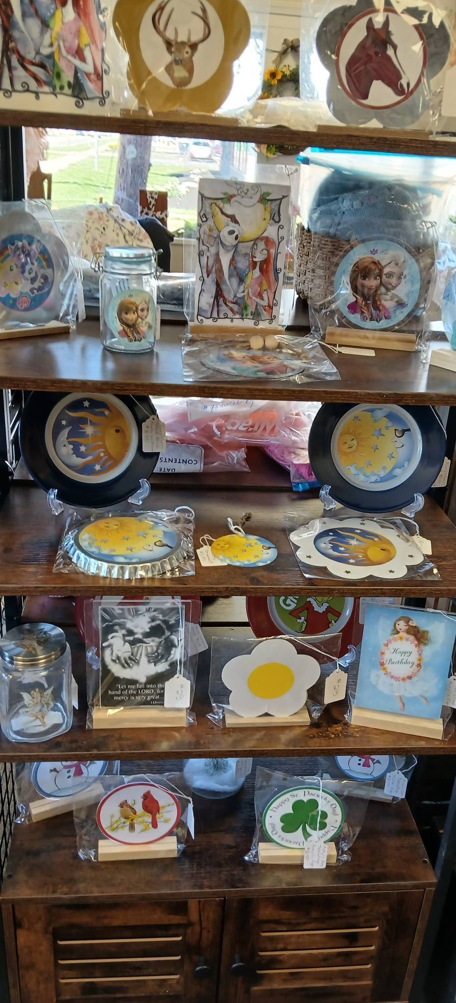 Wooden shelf displaying assorted decorative plates, bowls, and figurines in a shop or market stall