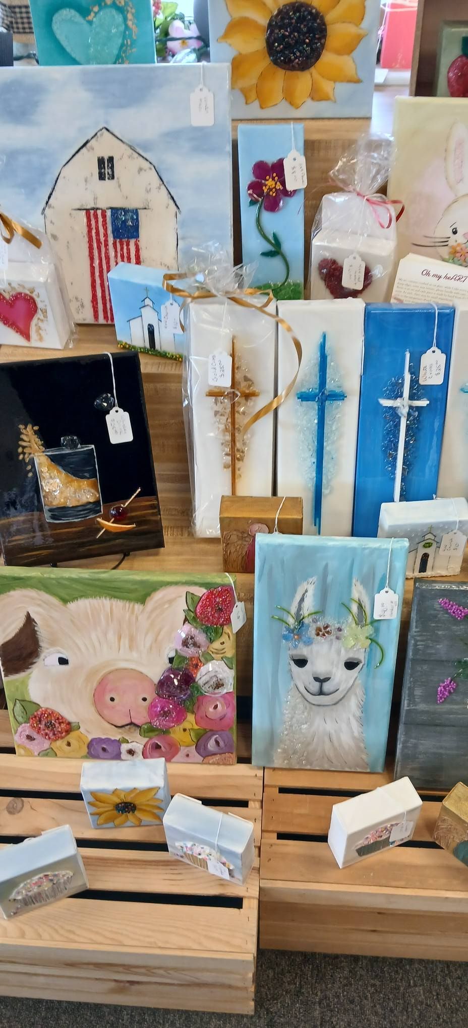 Craft fair display of small painted wooden cards and signs on easels, with flowers, animals, and houses.