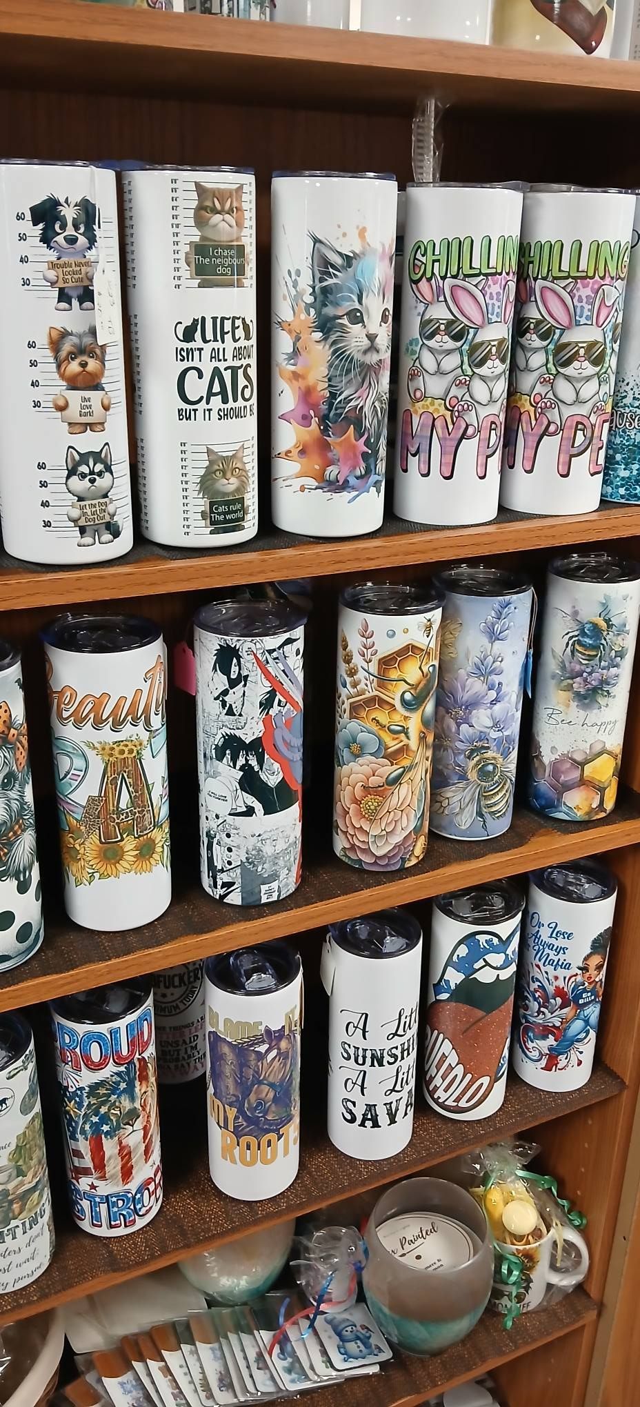 Shelves displaying rows of colorful patterned tumblers and mugs in a shop display