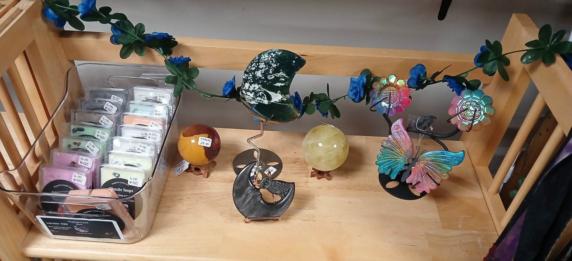 Assorted colorful decorative glass ornaments displayed on a wooden shelf