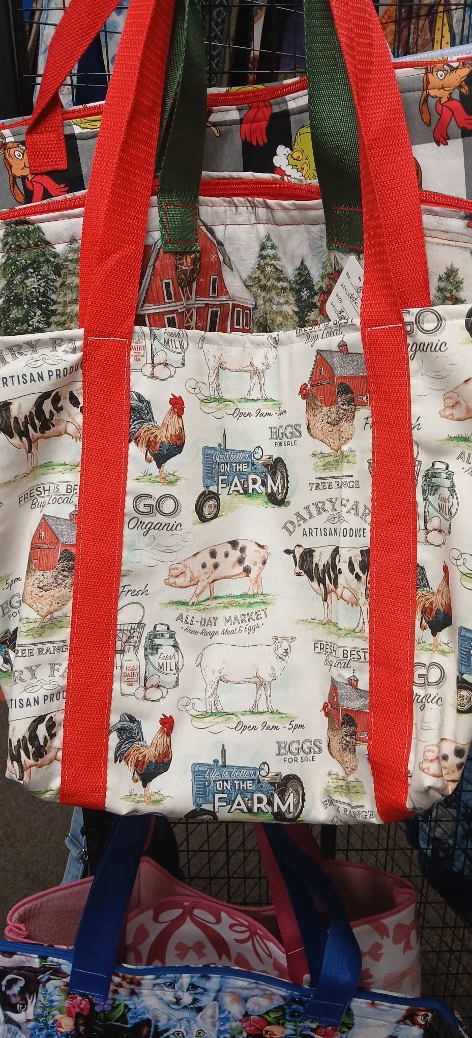 White tote bag with red straps and colorful animal illustrations hanging in a shop.