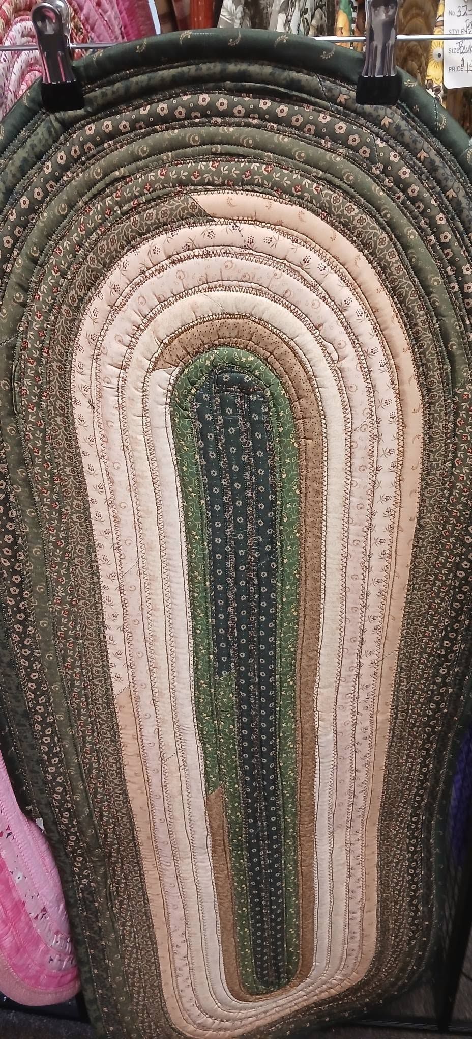 Colorful woven rainbow rug with concentric arches in green, pink, beige, and black hues