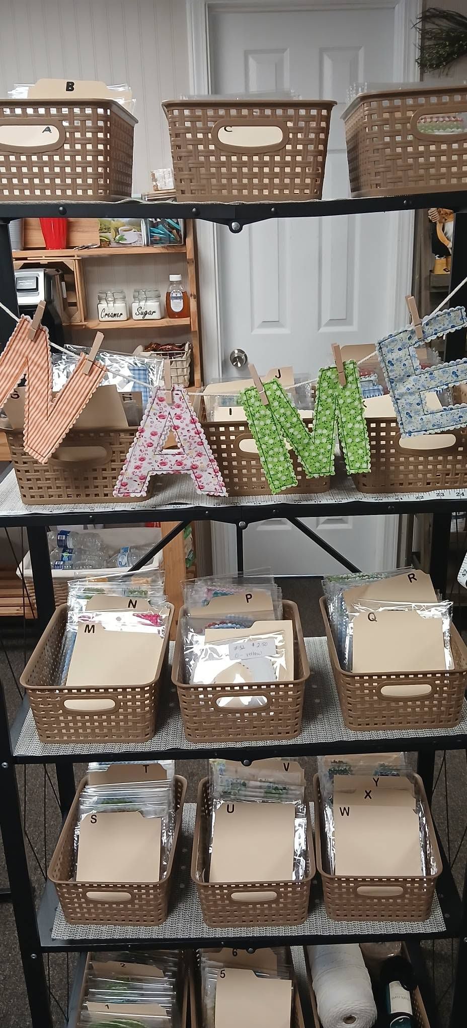 A shelf of woven baskets and decorative letter signs in a craft room or storage area.