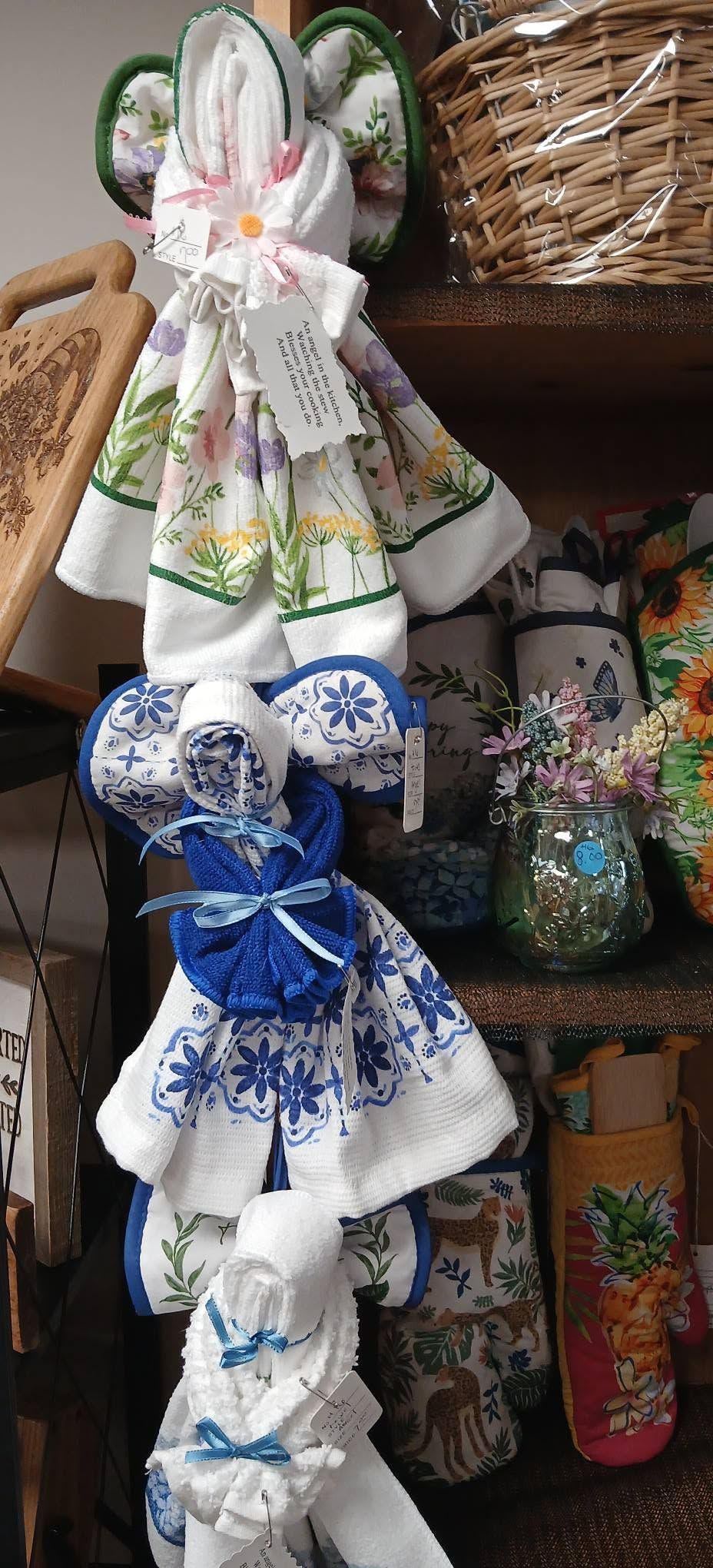 Decorative fabric dolls with blue and white bows hanging in a craft shop display