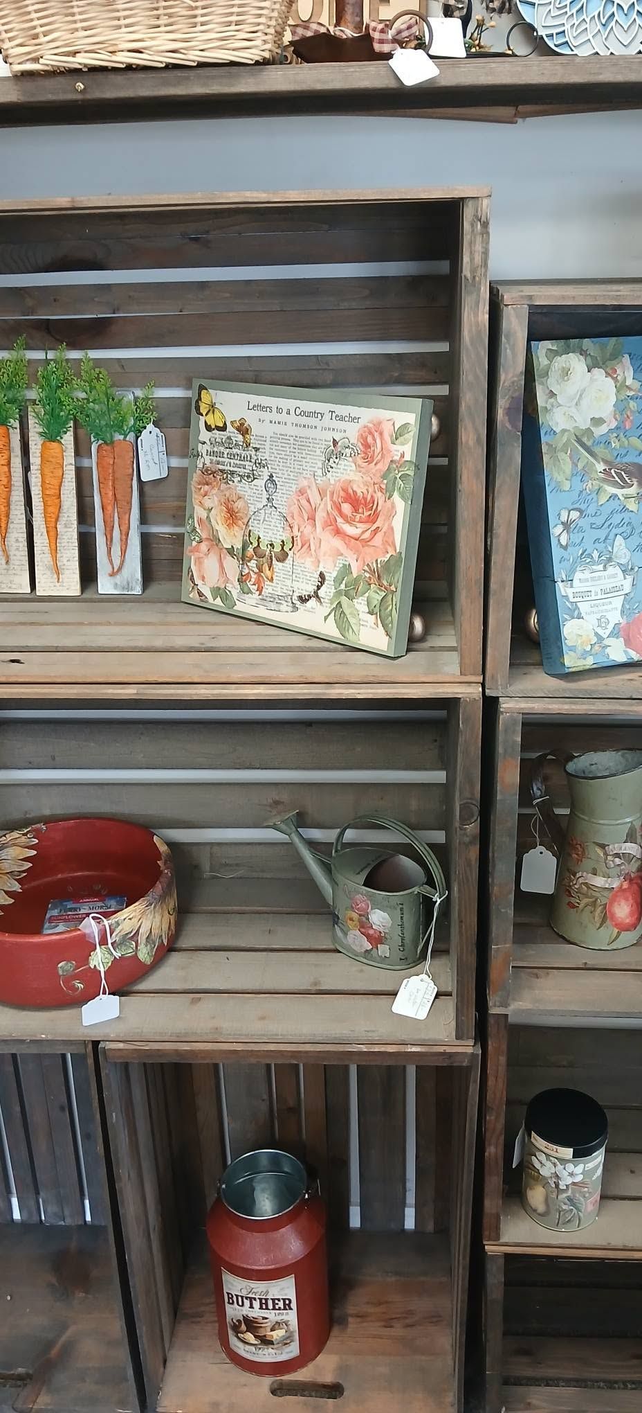Wooden shelf displaying decorative boxes, a red bowl, a mug, and small potted items indoors