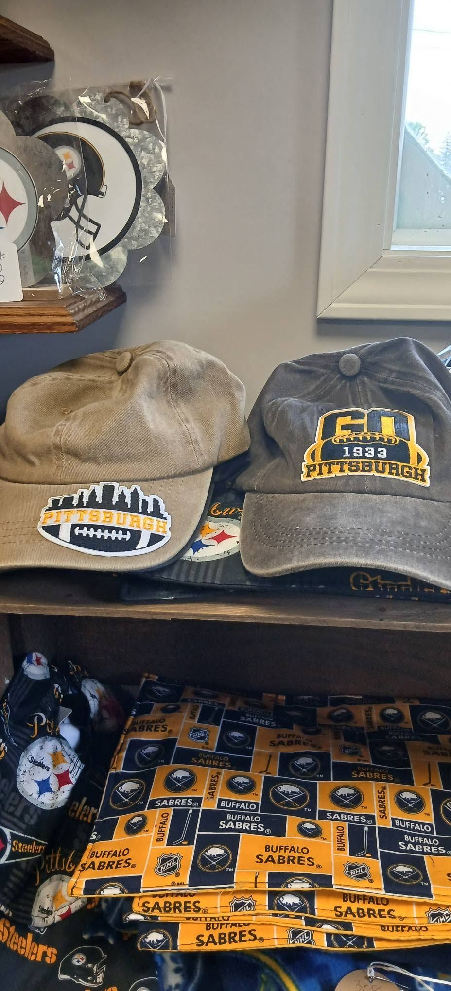 Assorted baseball hats and team apparel displayed on a shelf and table in a room
