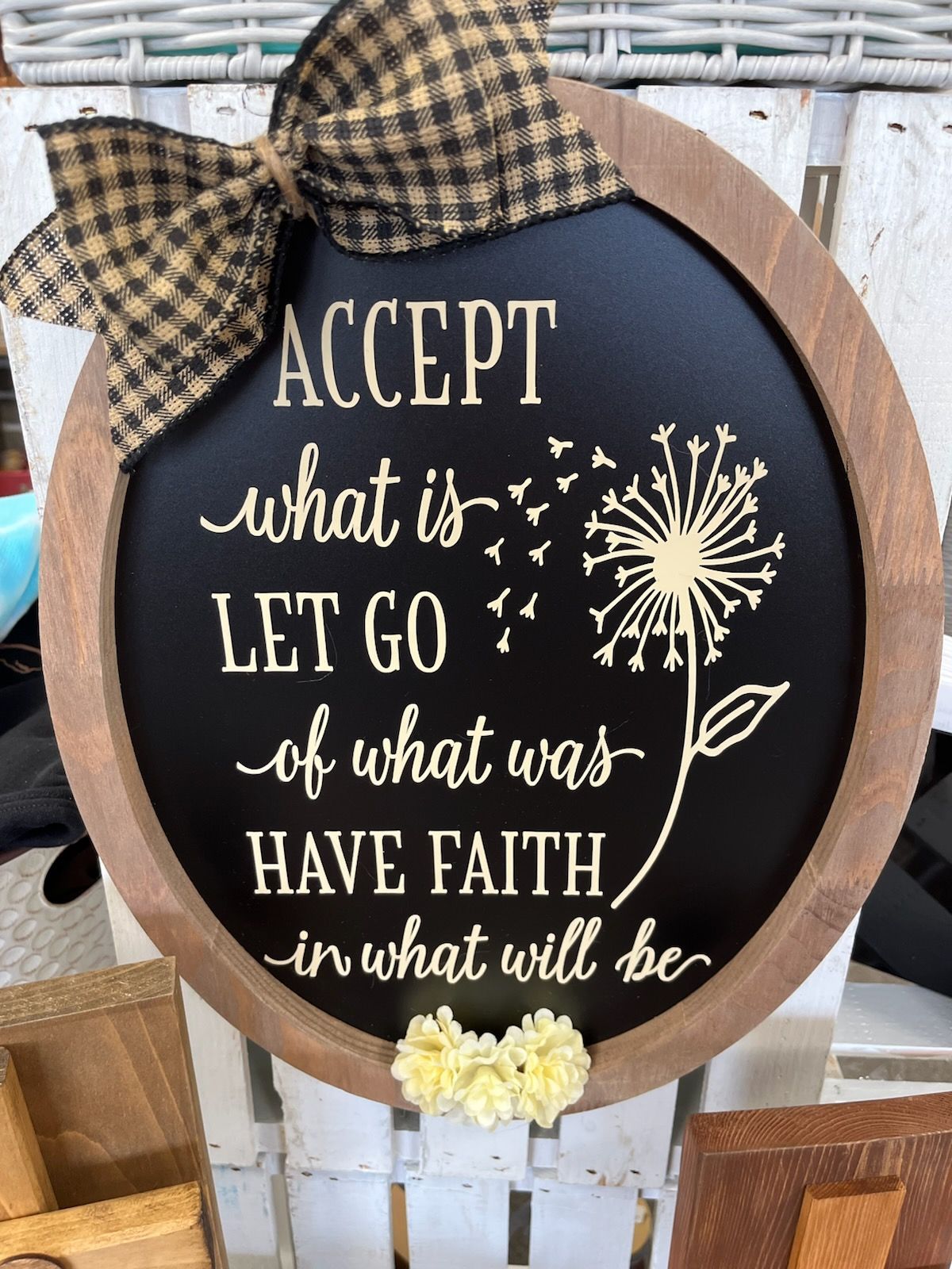 Round black sign with plaid bow reading “Accept what is, let go of what was, have faith in what will be.”