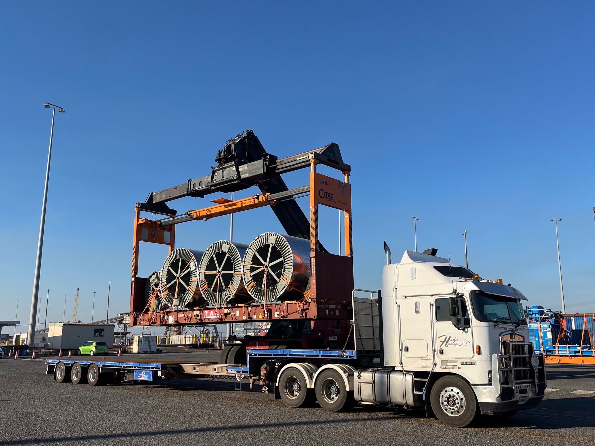 Truck hauling three large, metal coils secured in a frame under a blue sky. — Harker Haulage In East Arm, NT