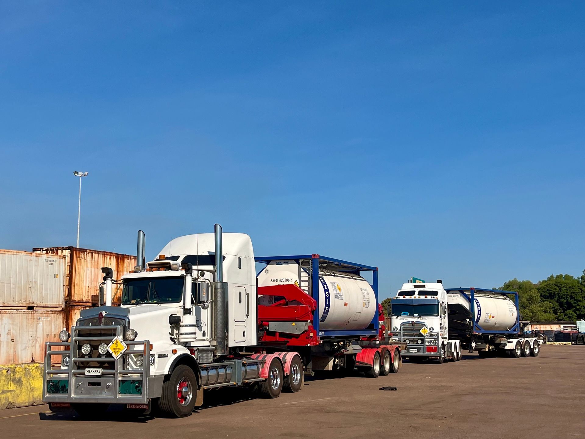 Two white semi-trucks with tanker trailers parked on a paved lot under a blue sky. — Harker Haulage In East Arm, NT
