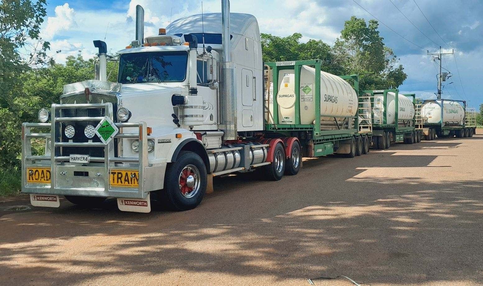 A White Truck is driving on a dirt road with white tanks of gas — Harker Haulage In East Arm, NT