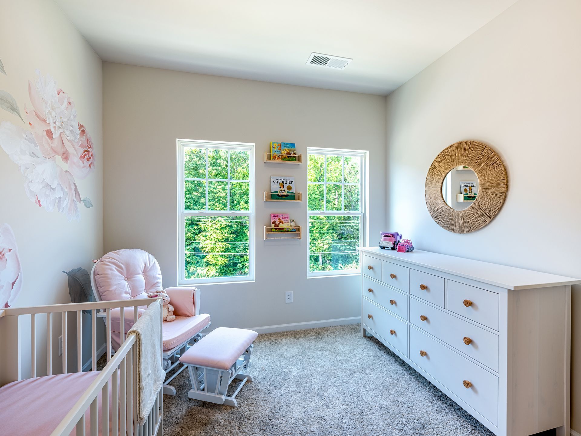 Picture of a staged baby room with a crib and pink chair