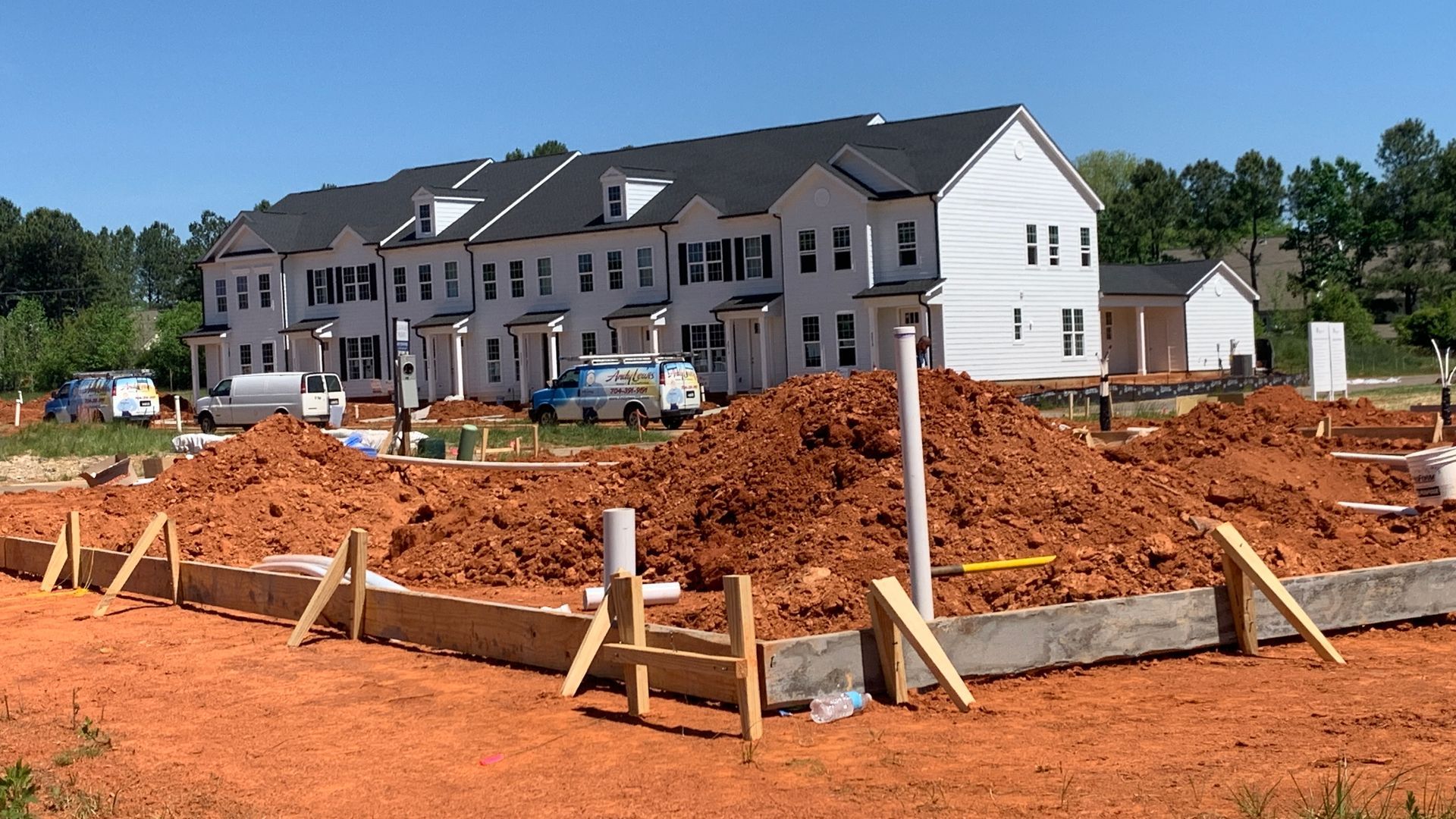 Early-stage residential construction site with dirt piles and tools, representing the beginning of the home buying journey.