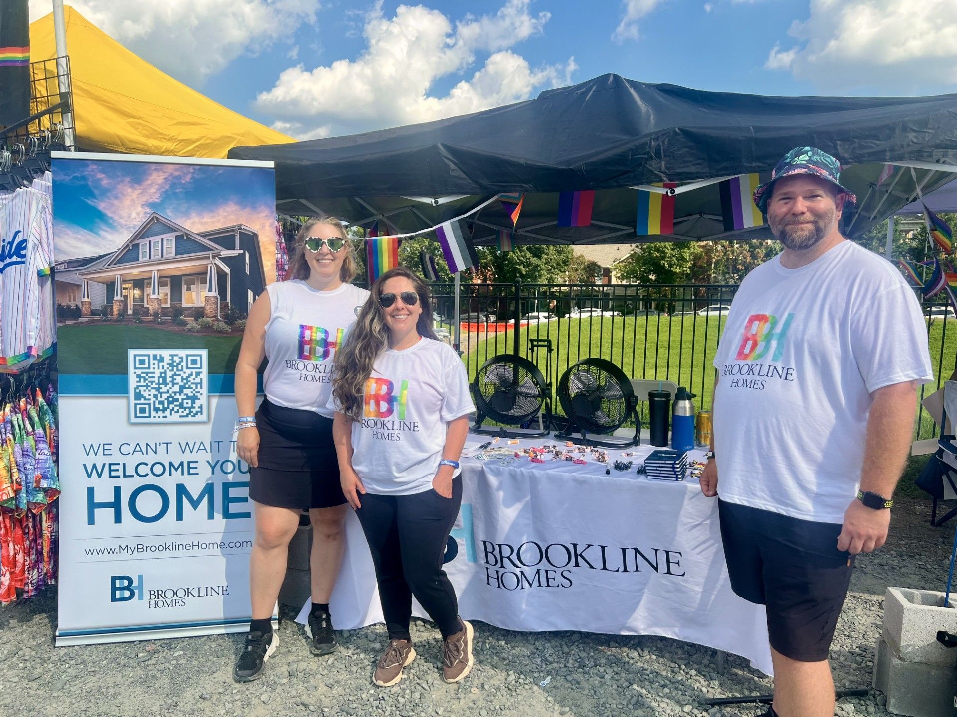 Photo of the Brookline Homes team standing next to a banner at the Charlotte Pride event table
