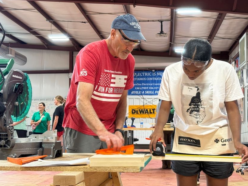 Man helping a young women learn how to measure and cut at a learning the trades event