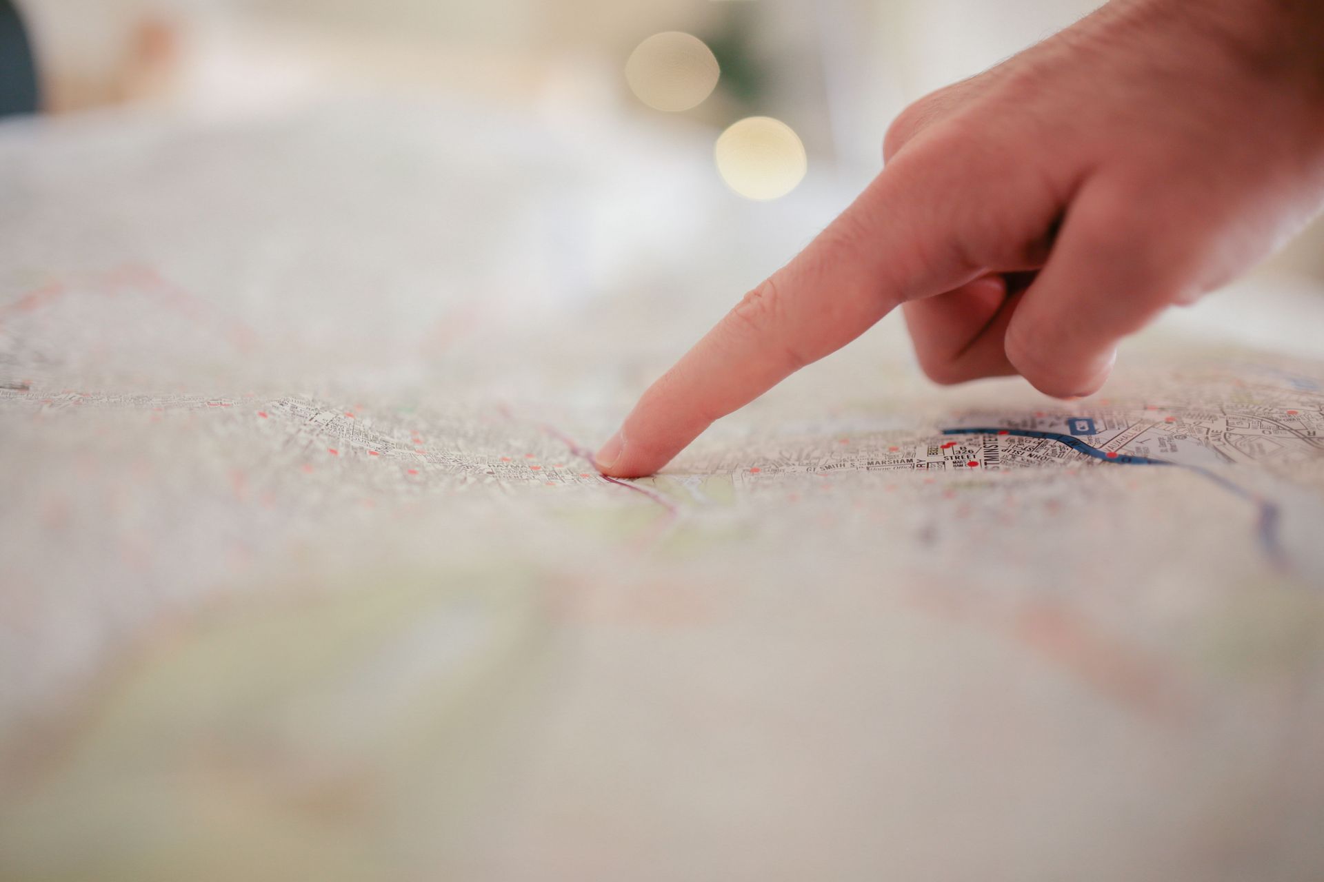 A hand pointing to a location on a flat map.