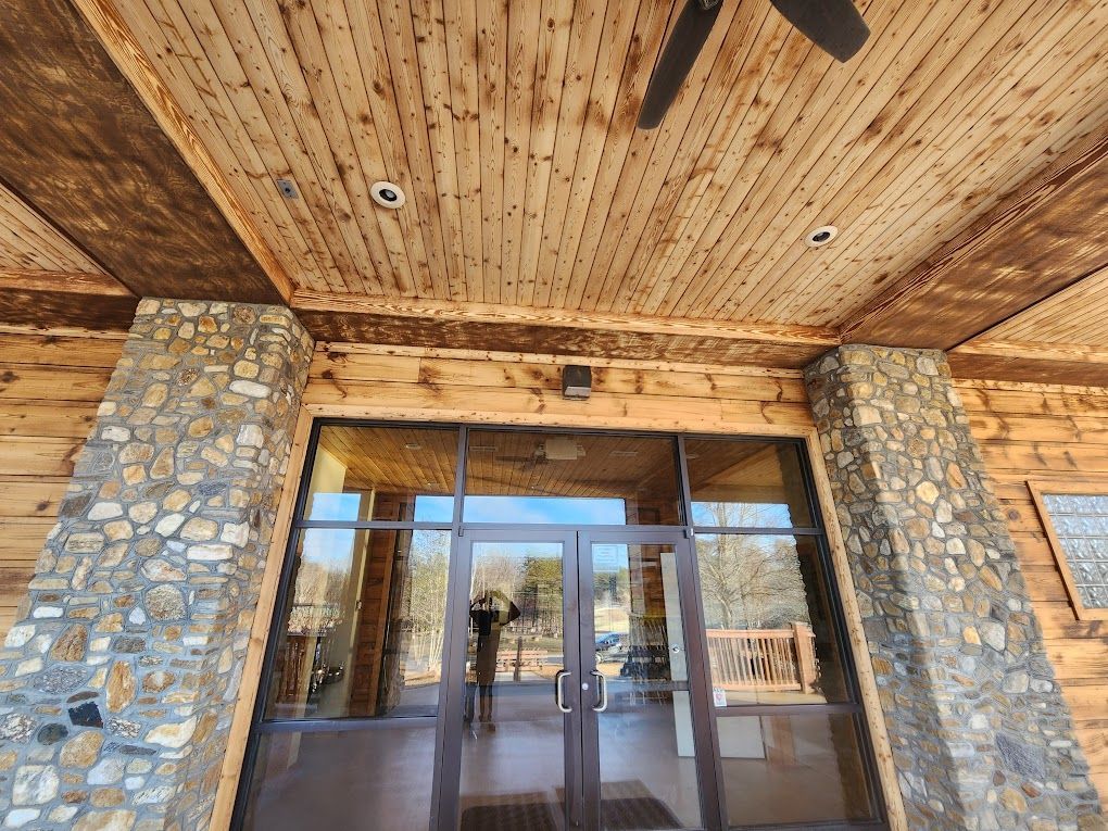 Stone-and-wood building entrance with glass doors and a wooden overhang