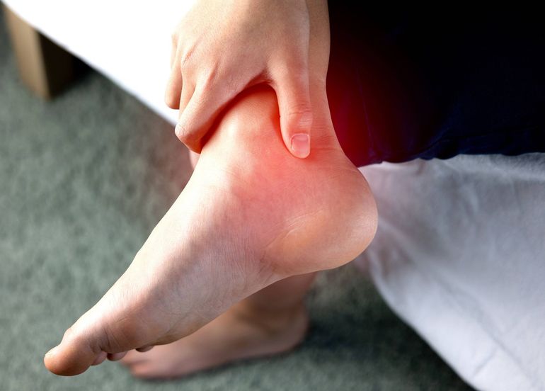 A person is holding their ankle in pain.